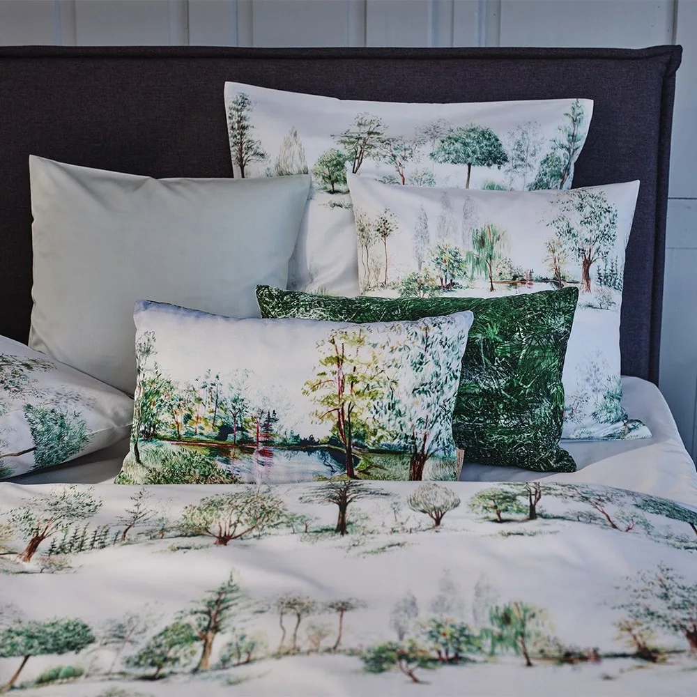 A bed with lots of pillows and a blanket with trees on it