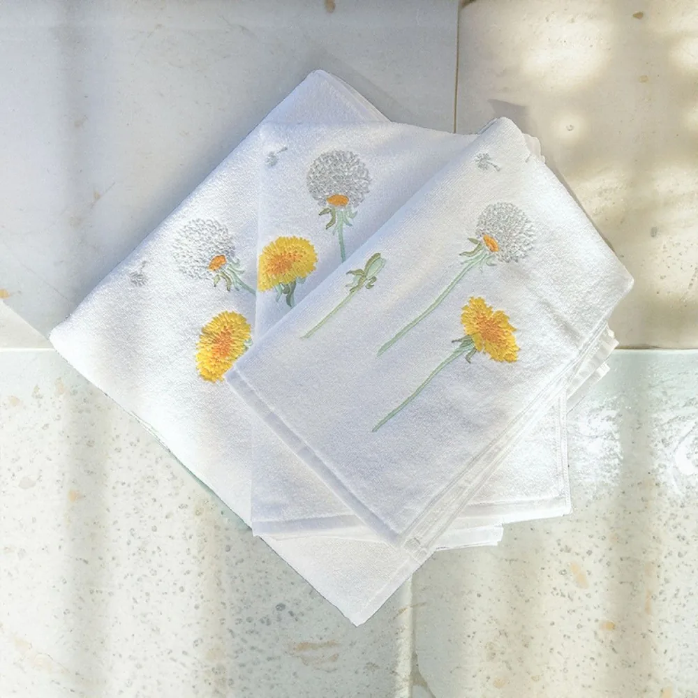 Une pile de serviettes blanches ornées de fleurs jaunes