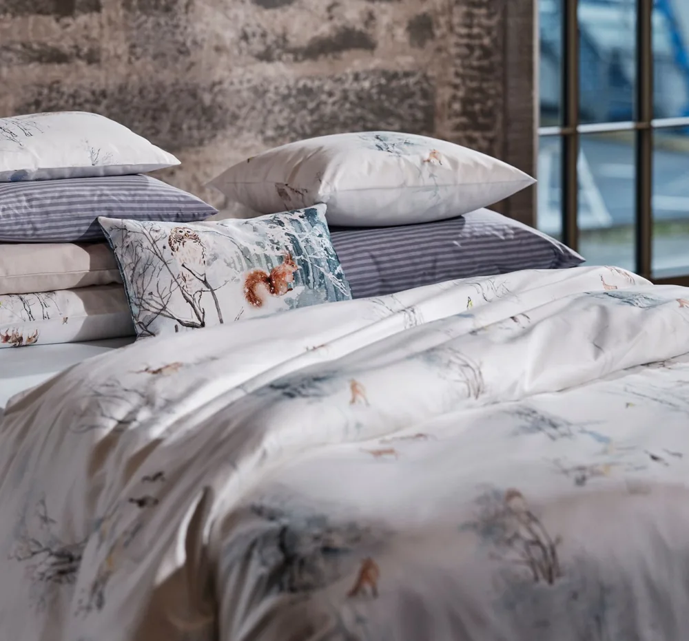 Lit avec une parure de lit à motifs floraux blancs et bleus et plusieurs oreillers.
