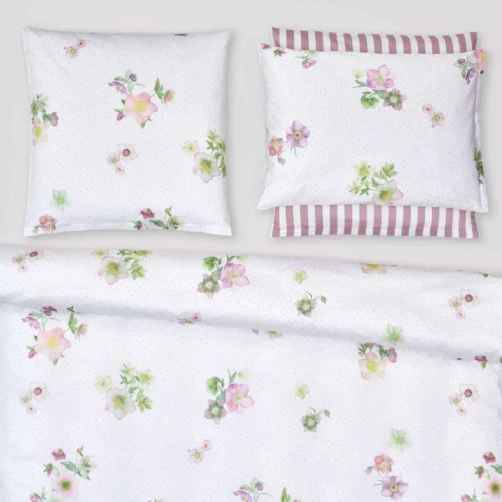 Un lit avec une couette à motifs floraux et des oreillers dessus