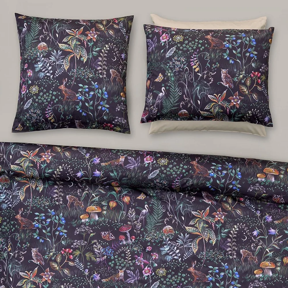 Un lit avec une housse de couette et deux oreillers à motif floral.