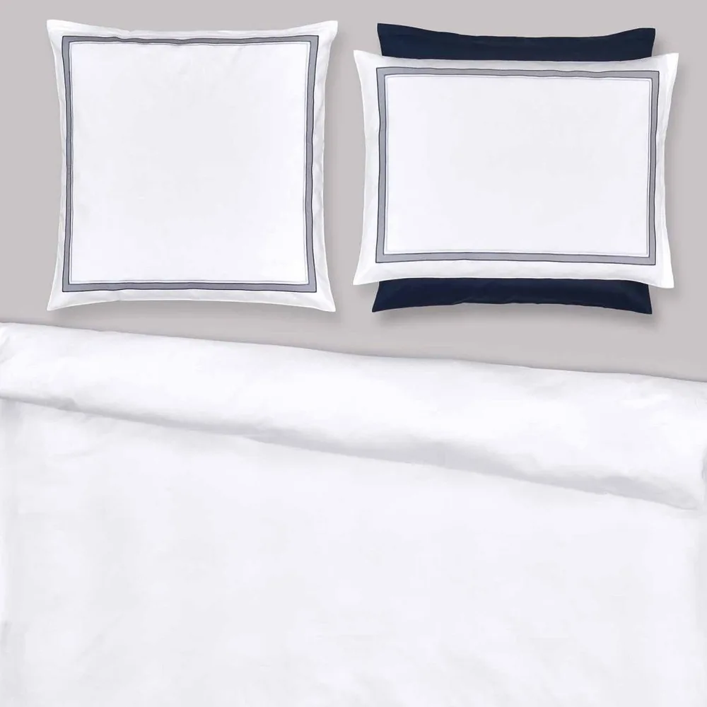 Deux oreillers sont posés sur un lit avec une couette blanche.