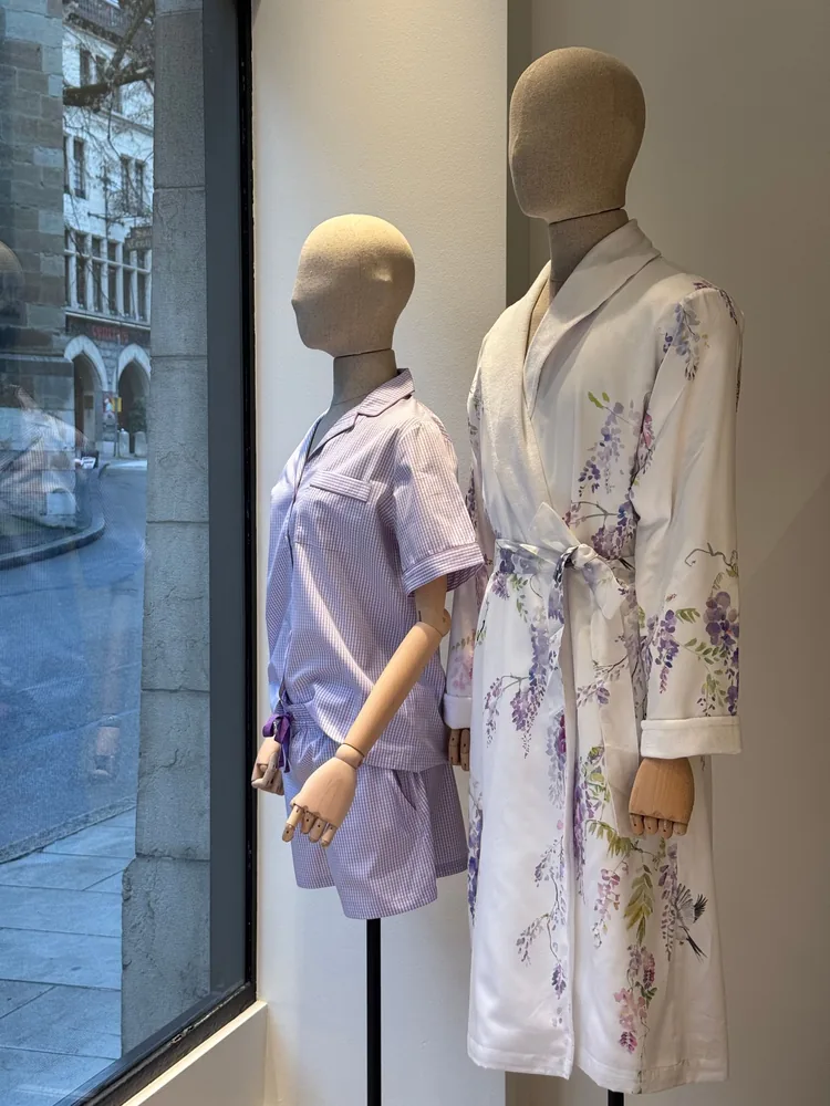 Two mannequins are standing next to each other in front of a window